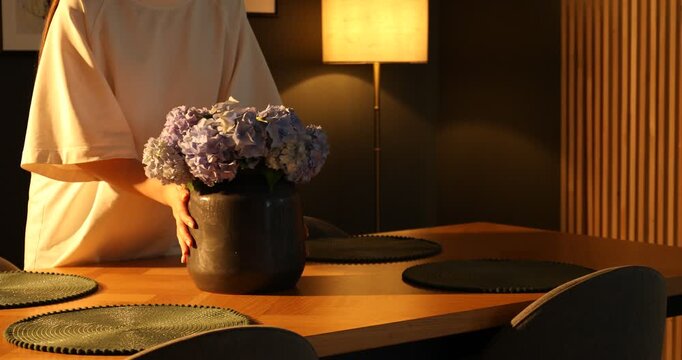 Woman setting dining table in dark room, closeup