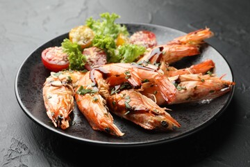 Tasty grilled shrimps served with salad on black table, closeup. Delicious seafood dish