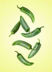 Jalapeno peppers falling against light green background