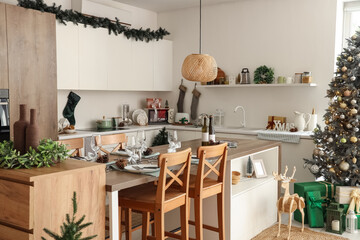Interior of light kitchen with Christmas tree, counters and dining table