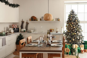 Interior of light kitchen with Christmas tree, counters and dining table