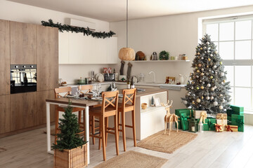 Interior of light kitchen with Christmas tree, counters and dining table