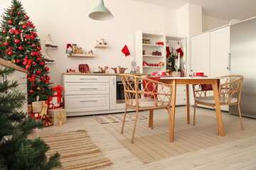Interior of light kitchen with Christmas trees, dining table and counters