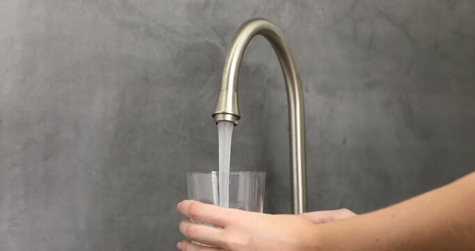 Water saving concept. Woman filling glass with tap water indoors, closeup