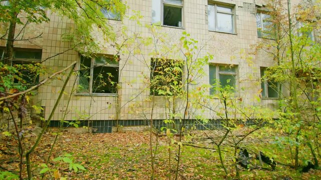 An overgrown, abandoned building of the medical unit in Pripyat, Ukraine, located within the Chernobyl Exclusion Zone. The structure, now reclaimed by nature, stands as a haunting reminder of the 1986
