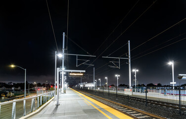 The modern Caltrain station in San Bruno, California, USA, on the San Francisco - San Jose line. The empty platform is illuminated under a dark night sky