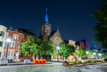 St. Lawrence Catholic Church, a historic Gothic Revival church on a street in Harrisburg, Pennsylvania, USA. The building is illuminated at night with a blue spire