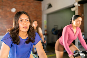 Women exercising on stationary bikes during spinning class