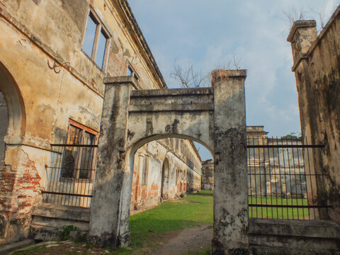 A perspective shot of the weathered Dutch colonial architecture of Benteng Pendem (Van den Bosch Fortress) in Ngawi, East Java, featuring a mossy, arched entrance and decaying brick walls.