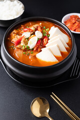 Korean food (Kimchi Jjigae), Kimchi soup with tofu and pork in Korean stone bowl eating with cooked rice and kimchi on black background