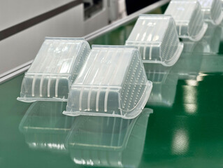Transparent plastic containers arranged on a green surface in a production facility for food...
