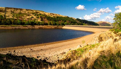 Sunny reservoir, low water, curving dam, hills, trees
