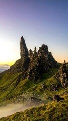 Dramatic rock formations at sunrise, mist-shrouded hillside