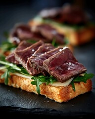 Close up of sliced beef steak on toast with arugula and cheese