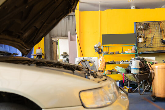 Focused woman inspects engine demonstrating her mechanical skills in auto repair shop. experienced small business entrepreneur mechanic female examines under vehicle hood, diagnosing car maintenance
