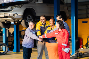 Team of mechanics stacking hands in unity at garage workshop, symbolizing cooperation, garage small business partnership, teamwork and professional collaboration for success in auto repair service