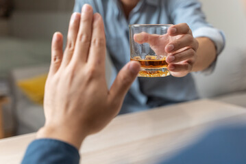 person deny alcohol drink from his friend
