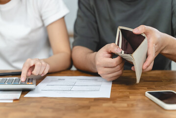 Stressed Asian couple looking at financial debt notice papers from bank.