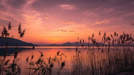 Obraz premium Sunset Lake with Mirror Reflection of Red Orange Pink Purple Sky Over Mountains and Grass