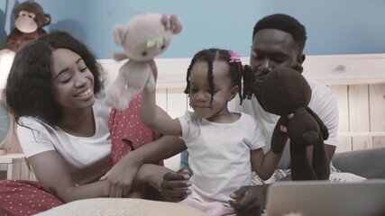 Authentic happy black couple playing with their little daughter and toys on bed. Smiling funny portrait of young african family at home. - Powered by Adobe