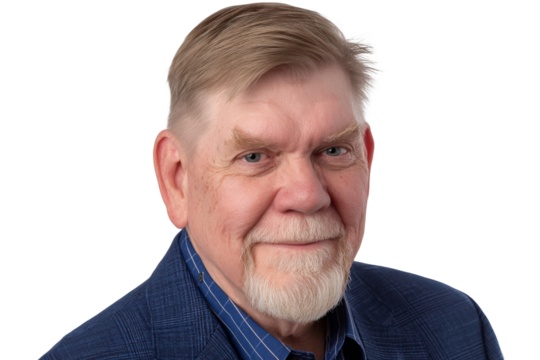 Elderly man with gray hair and beard in blue suit jacket smiling in front of a clean background showcasing an approachable and friendly demeanor