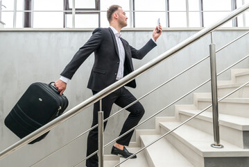 Businessman holding suitcase running on stairs in modern building