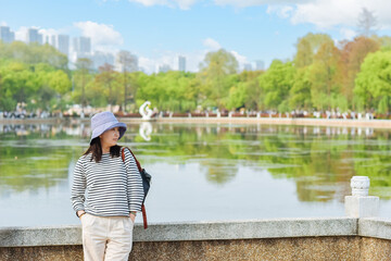 Fototapeta premium Beautiful Asian woman travels at Bitan Guanyu scenic area on the west bank of Wuhan East Lake in Spring in Wuhan city, Hubei province, China