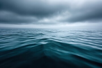 Ominous dark clouds rolling over a deep blue ocean with small waves, creating a dramatic and moody atmosphere
