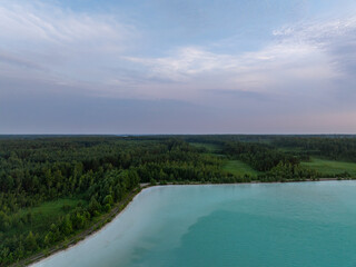 Aerial view of the turquoise waters of the Auvere ash pond or artificial lake, surrounded by lush green forests in Ida-Viru County, Estonia, near Narva-Jõesuu and the Gulf of Finland coastline.