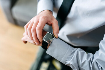 A man in a business suit checking a wrist watch on his hand
