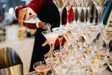 Person holding bottle of champagne serving Pyramid of Delicious Alcohol Crystal Glass with Champagne. Romantic Celebrations and Party Concept