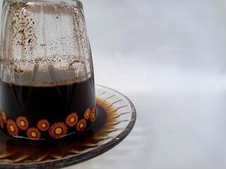 Freshly brewed black coffee served in an inverted cup with coffee beans spread around, representing lifestyle and cafe culture.