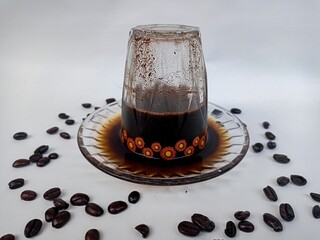 Freshly brewed black coffee served in an inverted cup with coffee beans spread around, representing...