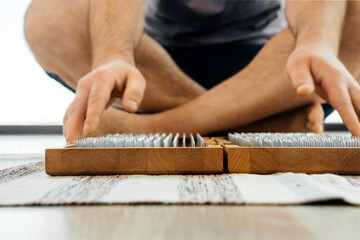 Cropped view of Man exercising yoga meditating and sitting on the floor near sadhu board