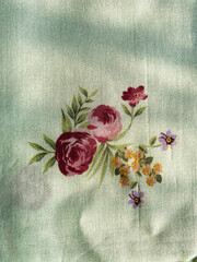 Graceful bunches of intricate rose flowers bloom across the green silk fabric.