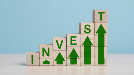 Wooden blocks spell INVEST with green arrows showing growth