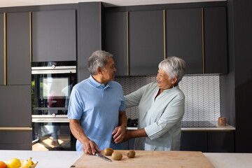 Senior couple preparing meal together in modern kitchen, sharing joyful moment