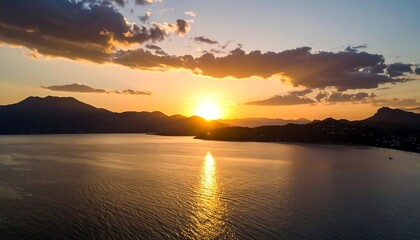 Obraz premium Sunset over calm water, mountain silhouettes