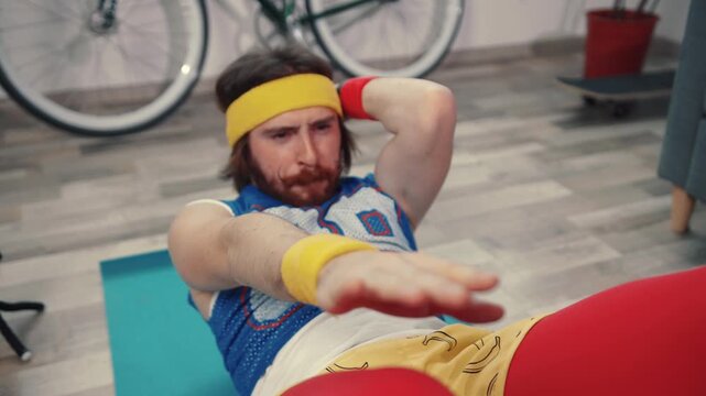 Funny fitness man doing abdominal crunches exercise failing to reach tasty hot pizza in the living room at home.