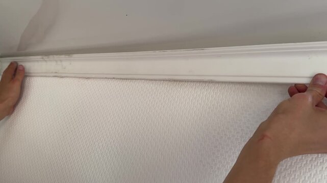 Man installing white ceiling molding at home interior. Renovation work, construction detail and household improvement