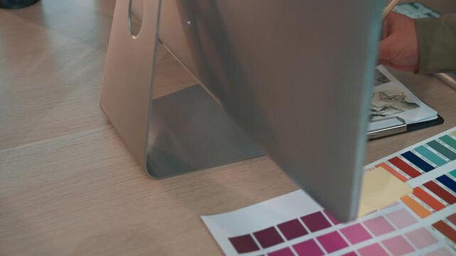 A modern workspace featuring a desktop computer alongside colorful samples and stationery. The setup promotes creativity and productivity, ideal for design professionals. SACTR