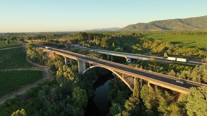 Aerial Drone Shot of Pan American Highway road bridge and railroad bridge crossing vineyards in Maule Valley in Chile in sunrise.