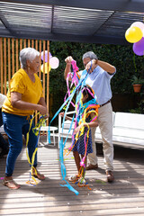 Grandparents and child playing with colorful streamers at outdoor family party