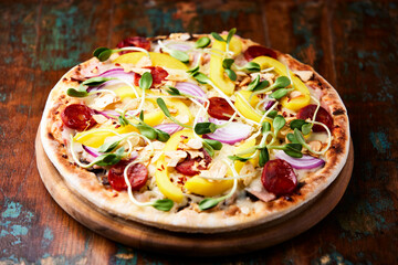Pizza with chorizo ​​sausage, mozzarella cheese and yellow pepper. Rustic wooden background. Soft focus.	
