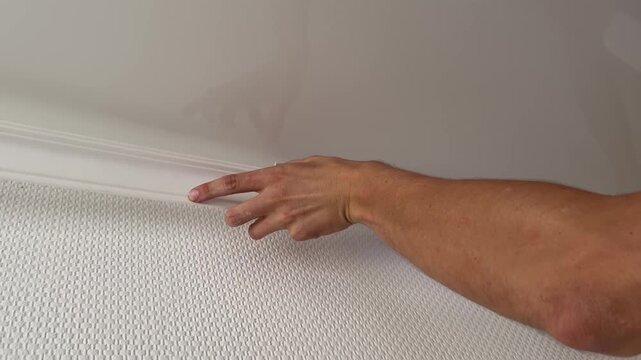 Man installing white ceiling molding at home interior. Renovation work, construction detail and household improvement