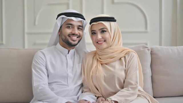 Arab Couple in Traditional Garb: A smiling Arab couple, dressed in traditional attire, sits closely, embodying happiness and unity, capturing the essence of culture and relationship.