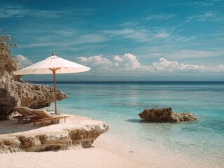 Fototapeta premium Serene beach scene with a sun umbrella and lounge chairs on a rocky shore, featuring a calm sea and distant clouds