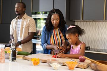 Family preparing meal together in modern kitchen, chopping vegetables and bonding