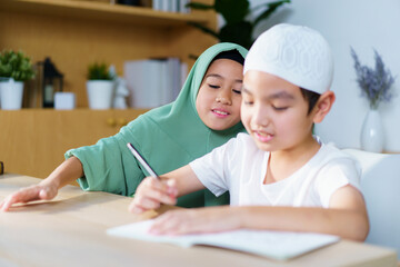 Muslim siblings study together, doing homework and reading in the study room.