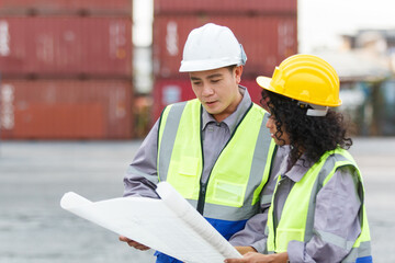 Container yard workers inspecting cargo containers together